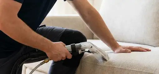 Professional upholstery cleaner deep-cleaning a fabric sofa with a handheld extraction tool, Tulsa, OK.